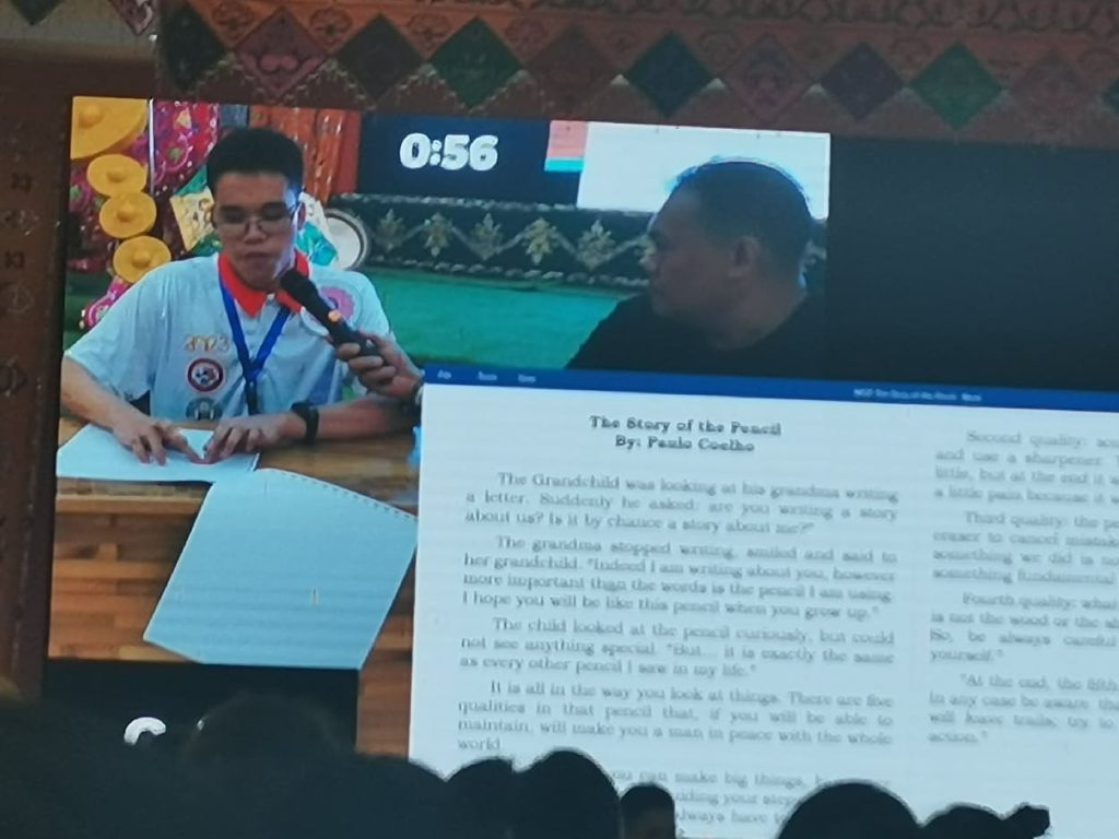 PNSB Student reads in Braille on a Podium on stage